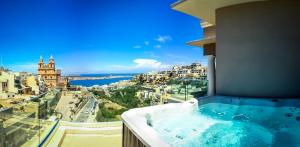 a hot tub on a balcony with a view of a city at Maritim Antonine Hotel & Spa in Mellieħa