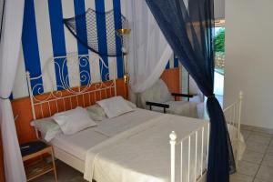 a bedroom with a white bed with blue and white curtains at Villa Verde Apartments and Rooms in Premantura