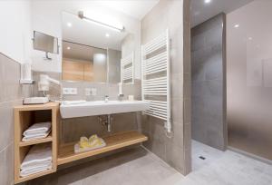 W łazience znajduje się umywalka, lustro i prysznic. w obiekcie Hotel Leonhard w mieście Leogang