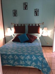 una camera da letto con un letto con un piumone blu e due lampade di Meublé de tourisme "Au bord de la Mare" a Salazie