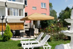 eine Gruppe Stühle und ein Regenschirm auf einem Hof in der Unterkunft Apartment-Hotel Rackwitz in Rackwitz