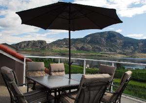 uma mesa e cadeiras com um guarda-sol numa varanda em Ciliegia Villa em Osoyoos