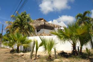 a white house with palm trees in front of it at BnBBonaire near the ocean in Kralendijk