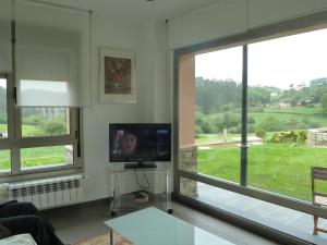 a living room with a tv and two windows at Apartamentos Arcos del Esva in Luarca