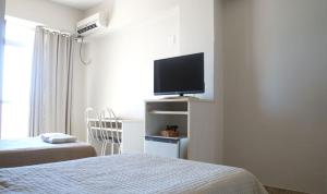 a hotel room with a bed and a flat screen tv at Manhuaçu Center Hotel in Manhuaçu