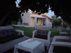 a patio with white chairs and a table and a house at Sea Sun in Plomari