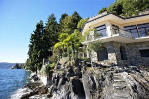 a house on a cliff next to the water at Villa Camelia in Verbania
