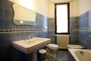 a blue tiled bathroom with a sink and a toilet at Villa Camelia in Verbania