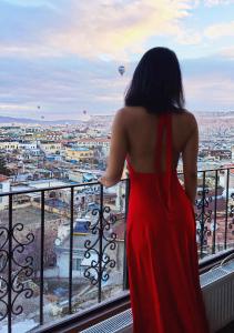 uma mulher num vestido vermelho olhando para uma cidade em Mirzade Konak Hotel em Goreme