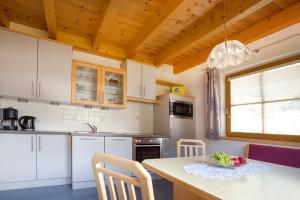 ナウダースにあるApart Alpenjuwelの白いキャビネット、テーブルと椅子付きのキッチンが備わります。