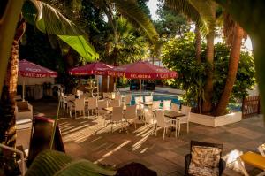 a group of tables and chairs with umbrellas and a pool at Hostal Alce in Playa de Palma