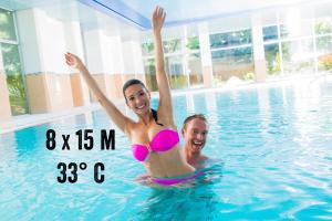 a man and a woman in a swimming pool at Badehotel Salina Maris – Wellness & Vintage in Mörel