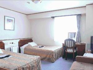 una habitación de hotel con 2 camas y una silla en Terminal Art Inn en Niigata