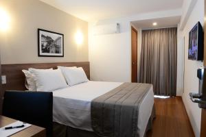 a hotel room with a bed and a desk at Nobile Hotel Juiz de Fora in Juiz de Fora