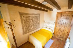 Un dormitorio con una cama amarilla y una puerta en El Mirador de Messía de Leiva, en Segura de la Sierra