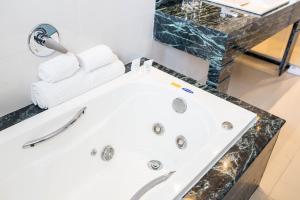 uma banheira branca com um balcão de granito preto em Américas Barra Hotel no Rio de Janeiro