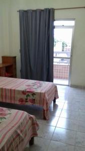 a room with two beds and a door with a window at Apartamento em Piúma-ES in Piúma