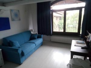 La Meridiana, monolocale in cascina ristrutturata في Boves: غرفة معيشة مع أريكة زرقاء ونافذة