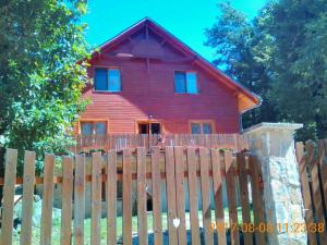 una casa roja detrás de una valla de madera en Dobogókő vendégház, en Dobogoko