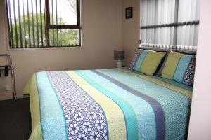 Ashbury Park Motel في تيمارو: غرفة نوم بسرير وبطانية زرقاء ونوافذ
