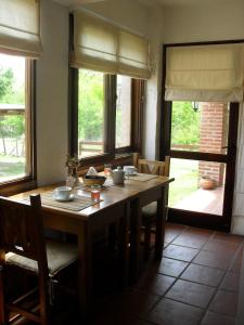 ein Esszimmer mit einem Holztisch mit Stühlen und Fenstern in der Unterkunft Portal del Río Posada in Santa Rosa de Calamuchita
