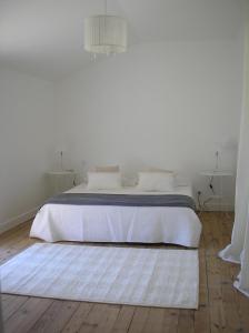 a white bedroom with a white bed with a rug at La Saudade in Saint-Péray