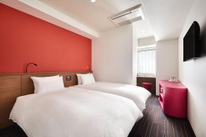a bedroom with two beds and a red wall at the b shimbashi toranomon in Tokyo