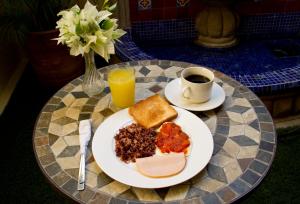 a table with a plate of breakfast food and a cup of coffee at Hotel Colibri in Managua