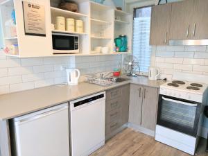 a kitchen with white cabinets and a white dishwasher at Highfield Private Hotel in Sydney