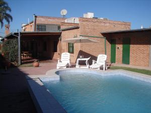 a pool with chairs and a table and an umbrella at La Niña in Salta