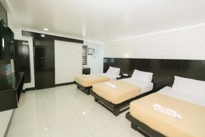 a hotel room with three beds and a tv at Sun Garden Hotel Tarlac in Tarlac
