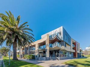 un edificio con una palmera delante de él en C-Scape water front apartment en Cowes