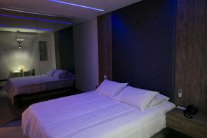 1 dormitorio con 2 camas y almohadas blancas en Hauss Excellence Motel en Sete Lagoas
