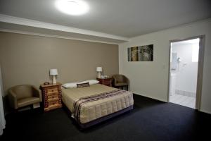 a bedroom with a bed and a chair at Centrepoint Motor Inn in Rockhampton