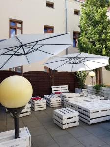 zwei Regenschirme und weiße Tische mit Sonnenschirmen in der Unterkunft Aparthotel W Pałacu in Krakau