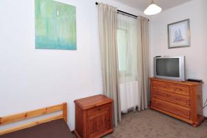 a living room with a tv and a dresser with a dresser at Borostyán 20 Vendégház in Sárospatak