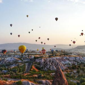 un montón de globos de aire caliente volando en el cielo en Eyes Of Cappadocia Cave Hotel, en Uchisar