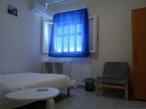 アテネにあるArtemidos Apartmentのベッドルーム1室(ベッド1台、椅子、青い窓付)