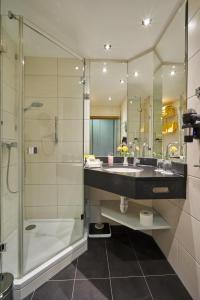 a bathroom with a shower and a sink and a mirror at Thermenhotel Apollo in Bad Füssing