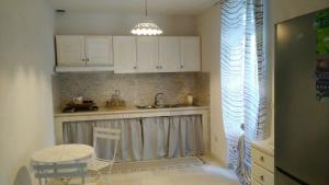 カロヴィーニョにあるCasetta di Andreaの白いキャビネット、シンク、テーブル付きのキッチンが備わります。