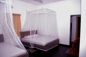 Schlafzimmer mit einem Bett mit Moskitonetz in der Unterkunft Bird Villa in Galle