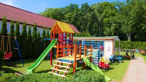 a playground with colorful play equipment in a yard at AIDA Domki Letniskowe - domki 5 min od MORZA - Plac Zabaw & ANIMACJE dla DZIECI, ROWERY gratis dla Gości in Rewal