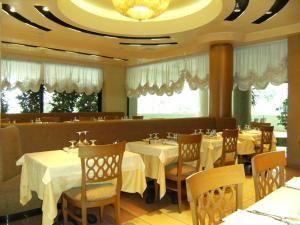 a dining room with tables and chairs and a chandelier at Hotel Europa in Bibione