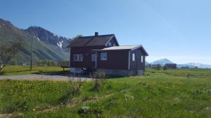 a small house in a field with mountains in the background at Grimsøy Lofoten House in Saupstad