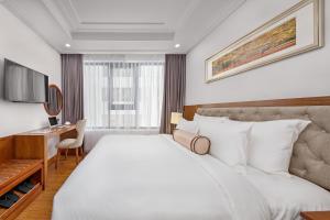 a hotel room with a large bed and a desk at Paris Deli Danang Beach Hotel in Danang