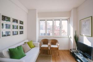 a living room with a white couch and a tv at Mãe de Água Apartment in Lisbon