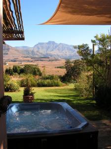 a hot tub in a yard with mountains in the background at Ama Casa Cottages in Champagne Valley