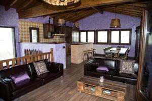 a living room with black leather furniture and a kitchen at Casa Rural el Ribero I in Llanteno