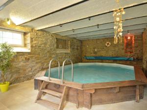 una gran piscina en una habitación con paredes de piedra y bañera de madera. en Cozy Holiday Home in Stoumont with Sauna and Jacuzzi, en La Gleize