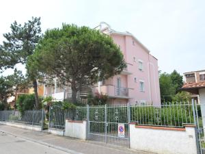 a pink building with a fence in front of a tree at Belvilla by OYO Lido Estensi Bilo Doria in Lido degli Estensi